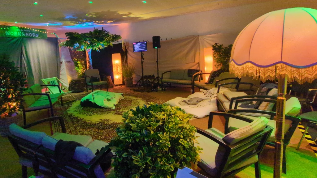 Das Garderobenfoyer mit Teppichen, Pflanzen, Bäumen, Couches und Lampen verwandelt in ein gemütliches einladendes Wohnzimmer.